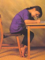 Picture of child bending over a school desk. Many hours of this can cause back problems and poor posture