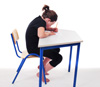 Child sitting at a school desk with bent back
